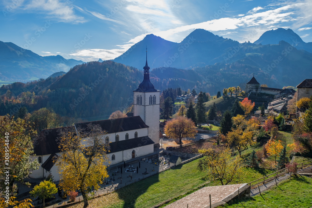 Backlight view with autumn light on the alps, church and cemetery in Gruyeres, Switzerland