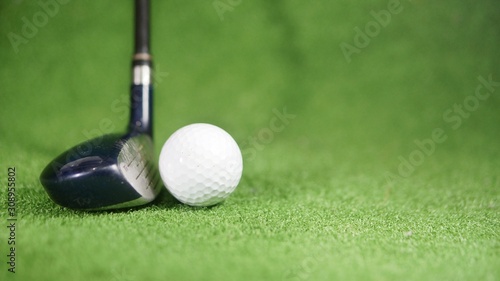 Hybrid golf club and golf ball on green grass