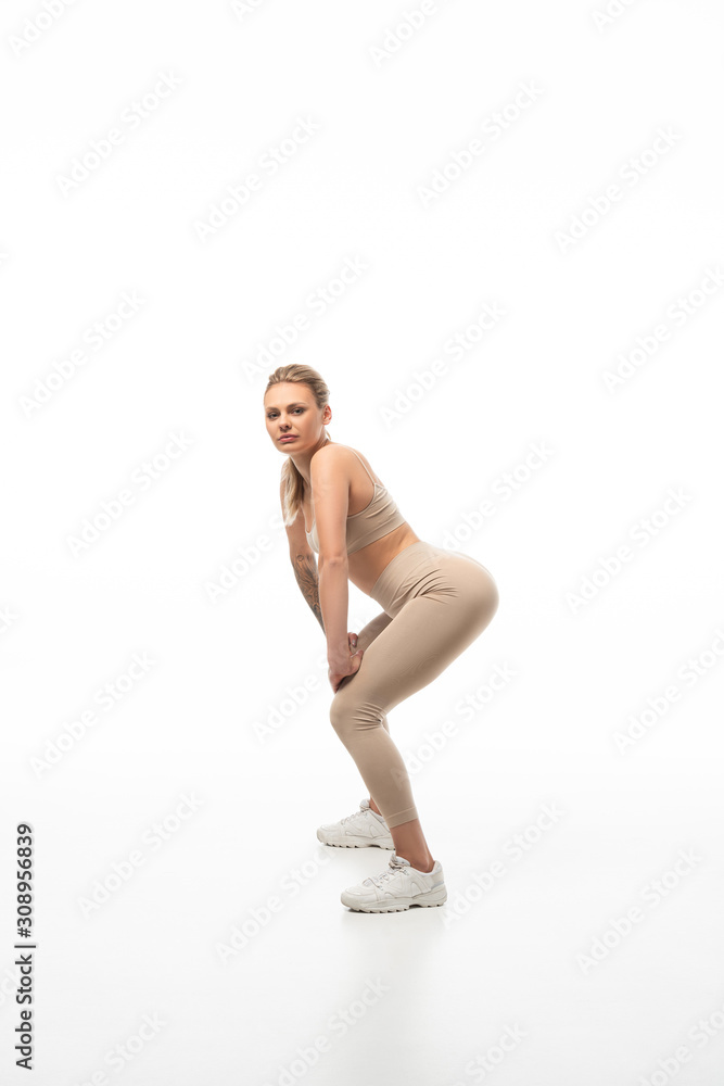 side view of blonde girl in beige leggings twerking isolated on white side view of blonde girl in beige leggings twerking isolated on white