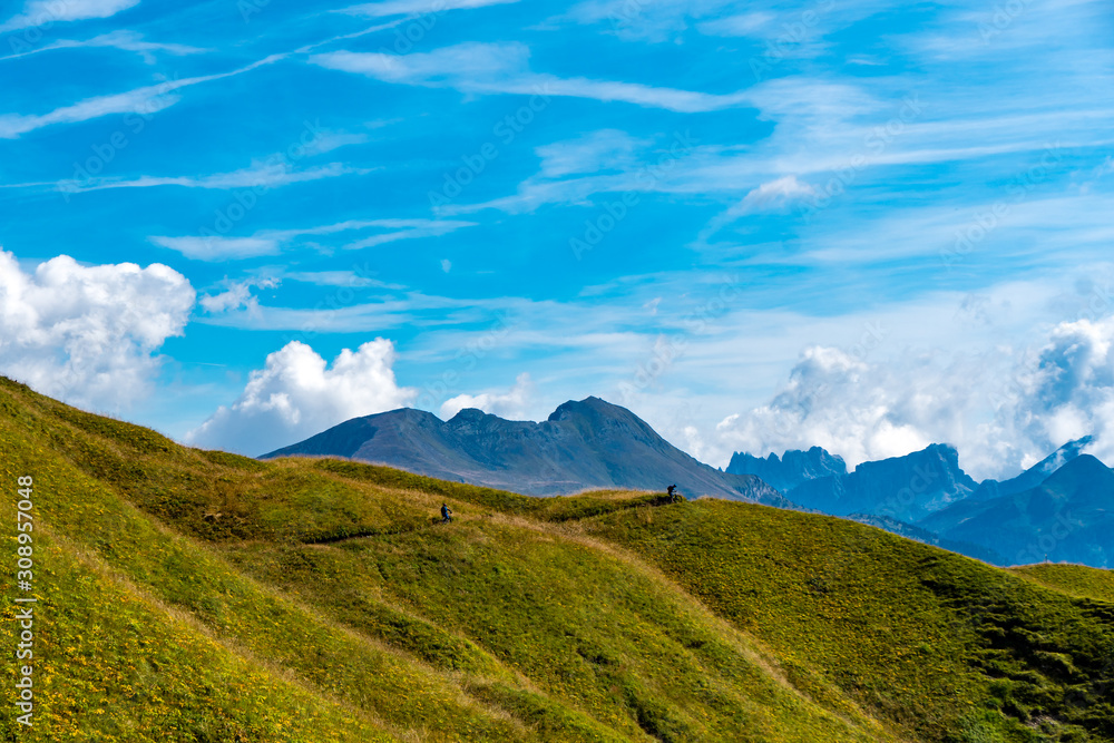 Mountainbiker auf Trail über eine Almwiese mit Blick auf die Dolomiten Berge