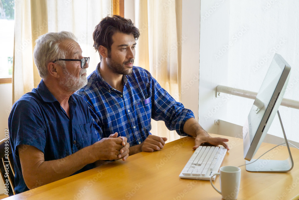 Middle aged male showing how to using internet to his father for make payments through internet, online security