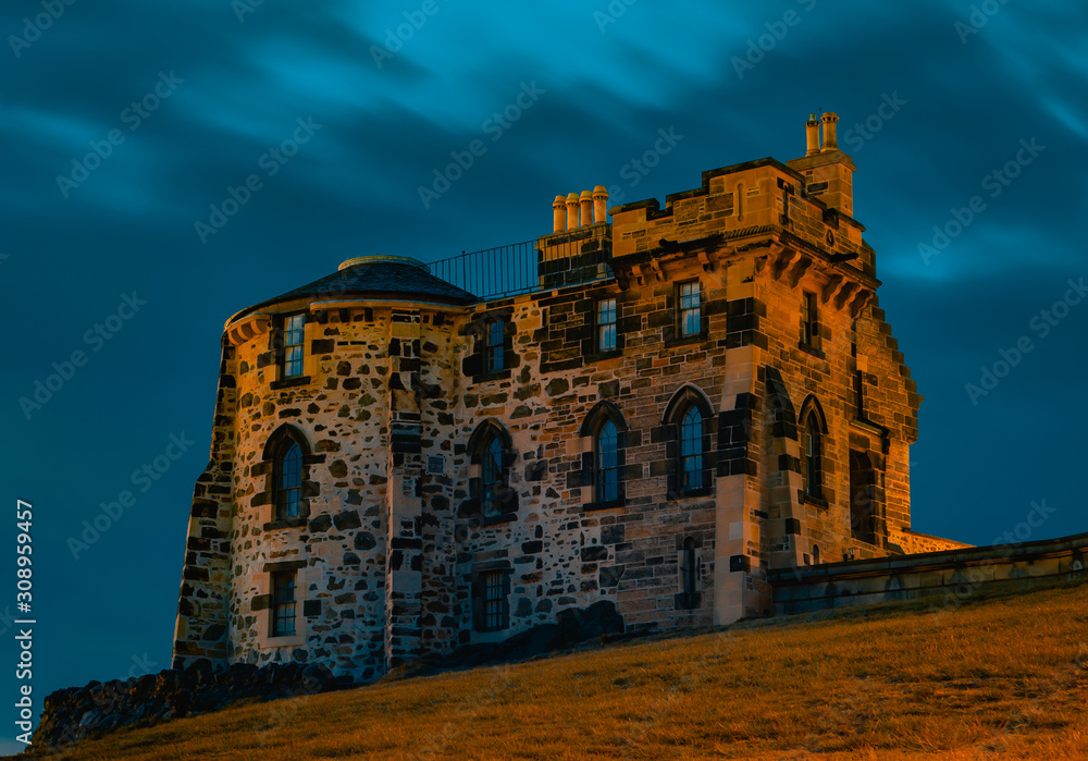 Sandstone building with arched windows, chimneys and circular side on Calton Hill in Edinburgh, Scotland.