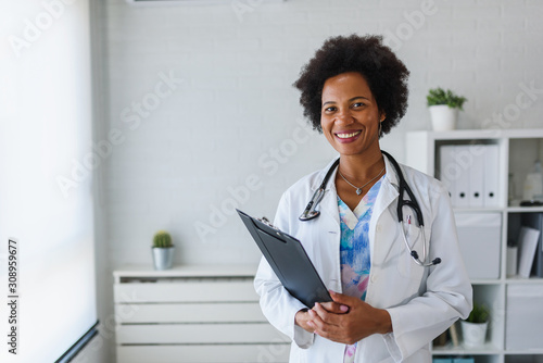 Fototapeta Portrait of female African American doctor standing in her office at clinic