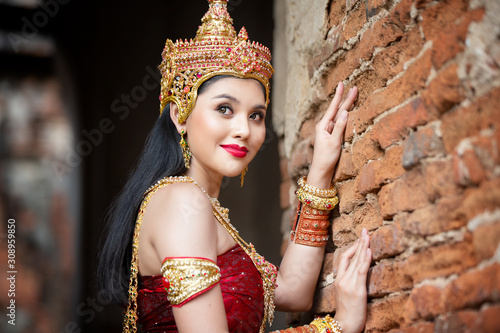Portrait of woman with traditional costume in thai temple against statue of buddha in thailand