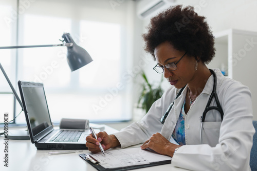 Bild auf Leinwand Serious concentrated African American doctor working in her office at clinic