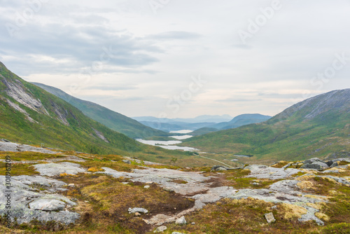 Green mountain landscape with a valley and several lakes. In the foreground a rocky plateau with yellow lichen. View from high perspective. Senja, Norway. © Ida Haugaard Olsen