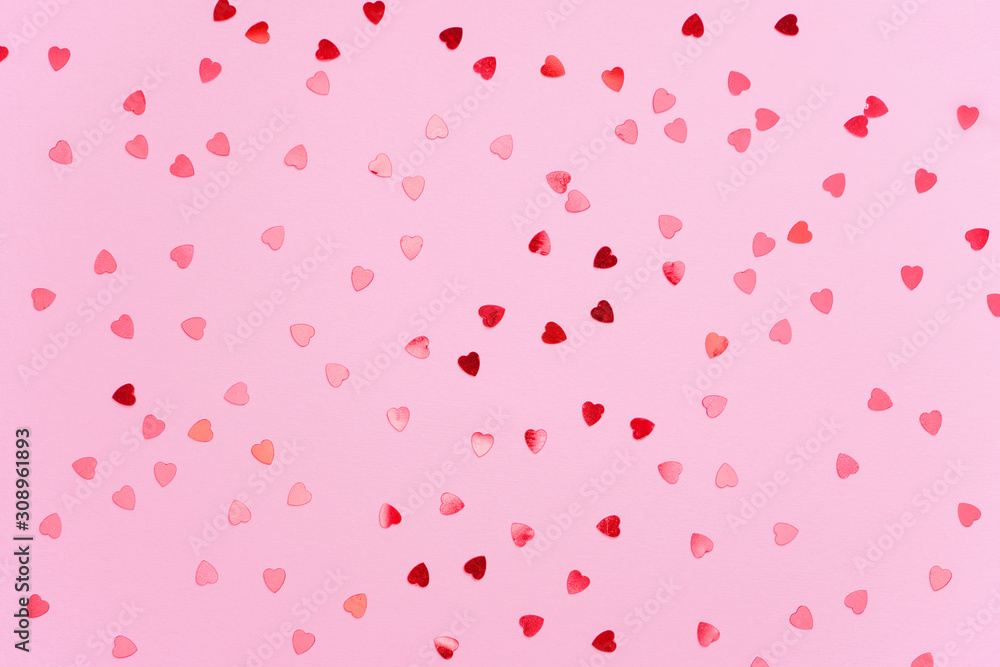Red heart shape confetti pattern on light pink background. Valentine, love, wedding concept. Top view, flat lay