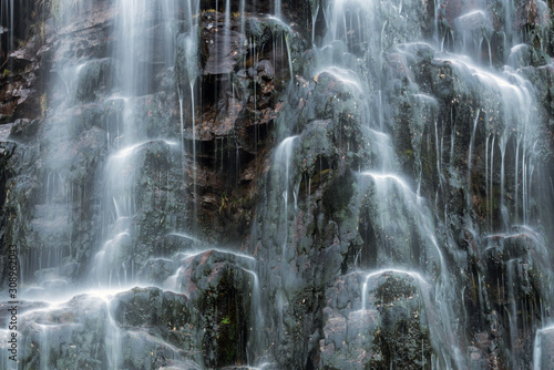 Closeup of flowing waterfall and green mossy rocks outdoors in nature. Texture and pattern concept.