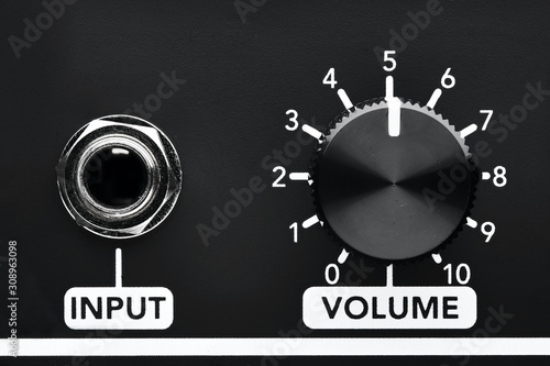 Close up detail of volume control knob and input jack of a black guitar amplifier photo