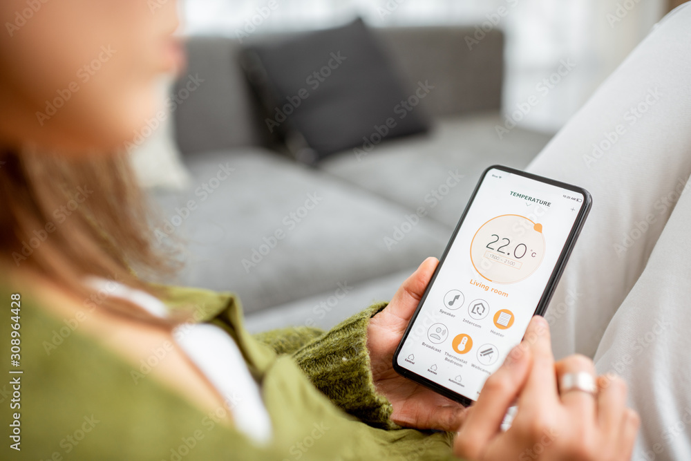 Controlling heating temperature with a smart phone, close-up. Concept of a smart home and mobile application for managing smart devices at home Controlling heating temperature with a smart phone, close-up. Concept of a smart home and mobile application for managing smart devices at home