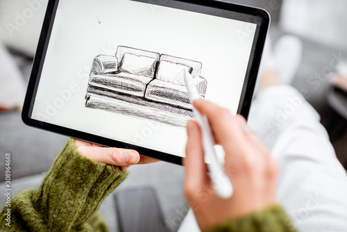 Obraz na plátně Woman designing furniture, sketching sofa on a digital tablet with wireless pen