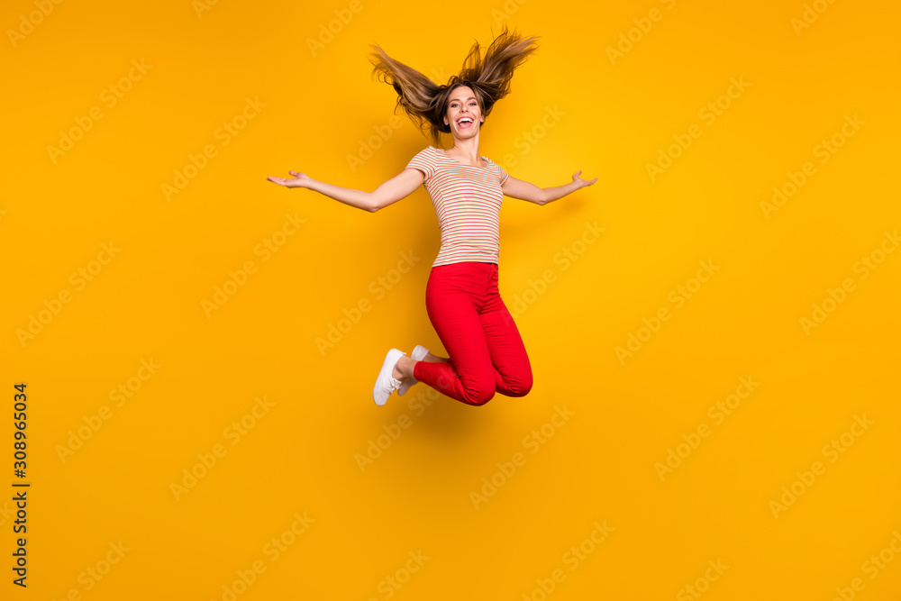 Full size photo of childish cheerful funky girl with hairdo flying jump have free time hold hands aside wear casual style clothing isolated over yellow color background Full size photo of childish cheerful funky girl with hairdo flying jump have free time hold hands aside wear casual style clothing isolated over yellow color background