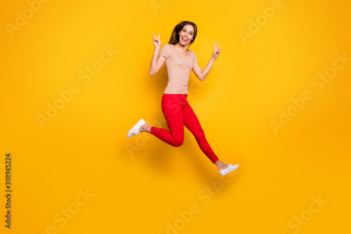 Full size photo of lovely nice girl jump have spring free time make v-sign wear casual style clothes isolated over yellow color background