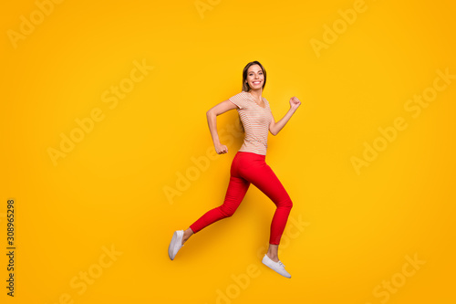 Full body profile photo of funky lady jumping high rushing discount shopping store addicted person wear casual striped t-shirt red trousers isolated yellow color background © deagreez