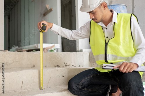 Fototapeta Engineer checking defect in construction site measure dimention of stair height