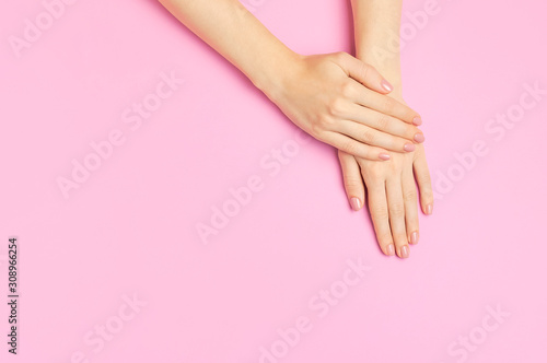 Stylish beautiful gentle manicure. Hands of young woman on pink background top view flat lay copy space. Natural nails, gel polish, self-care, beauty and fashion. Nail care, Beauty salon advertisement
