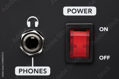 Power on and off electrical switch button and headphone input jack on a black amplifier