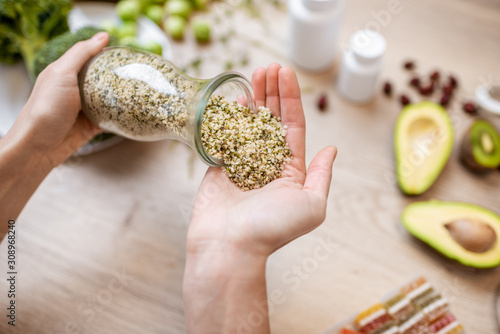 Holding hemp seeds at the table with healthy vegan food ingredients and supplements, top view. Concept of Marijuana as a new trend in food and cosmetic industry photo