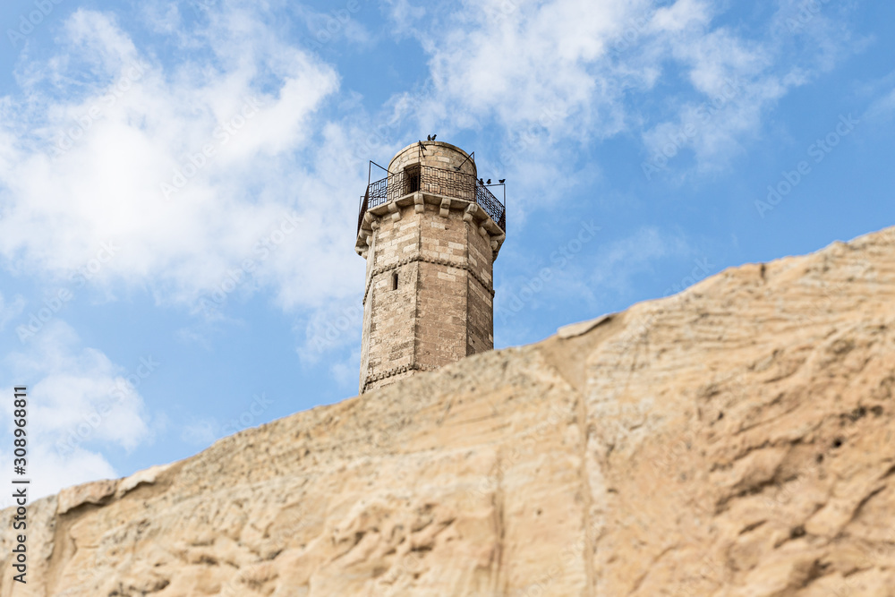 The minaret of the mosque located on the territory of the grave of the prophet Samuel rises above the remnant wall of the crusader fortress of Mount of Joy near Jerusalem in Israel