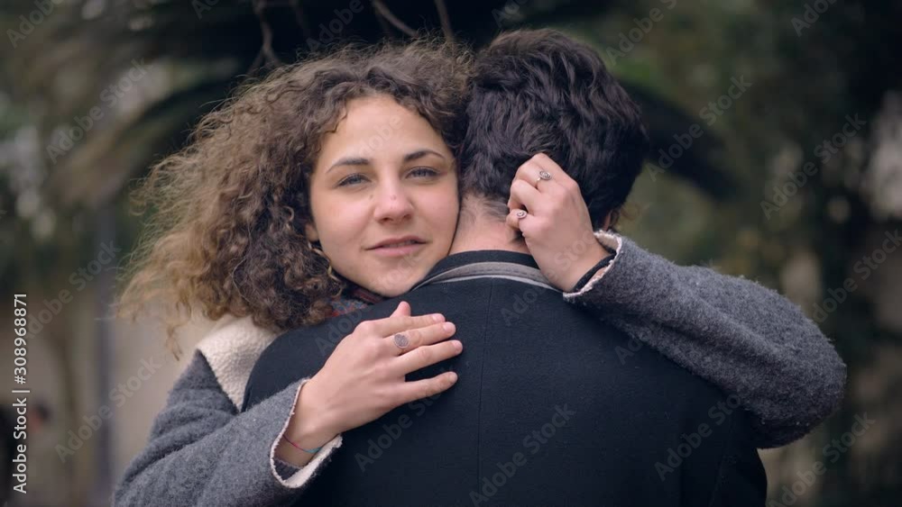 couple embracing at the park.She making gesture of silence at camera.Secret sign couple embracing at the park.She making gesture of silence at camera.Secret sign
