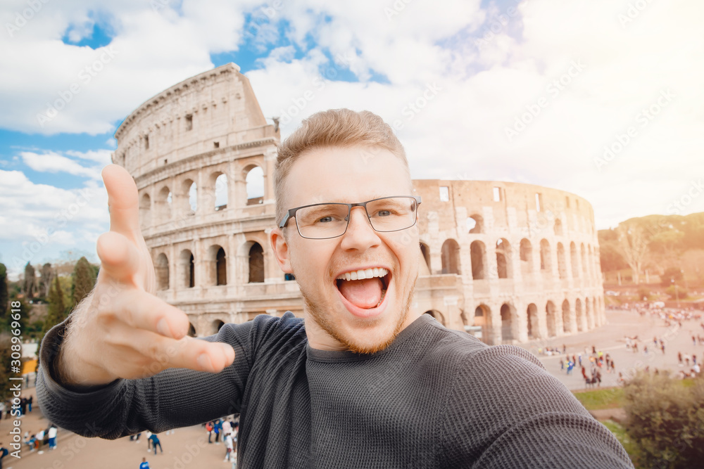 Happy young man making selfie in front of Colosseum in Rome, Italy. Concept travel trip