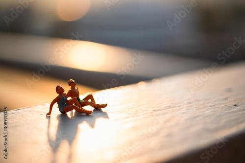 Miniature people wearing swimsuit relaxing with natural sunlight , Summer time concept
