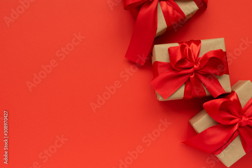 Gift boxes wrapped brown craft paper and red ribbon on red background. Valentines day or Christmas celebration concept. Top view