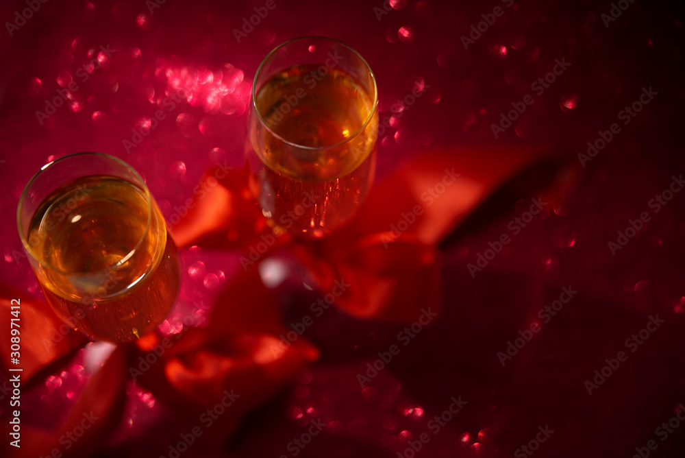 Top view on two glasses of champagne decorated red ribbon on red glittering background. Valentines day or Wedding celebration concept. Copy space. Soft focus Top view on two glasses of champagne decorated red ribbon on red glittering background. Valentines day or Wedding celebration concept. Copy space. Soft focus