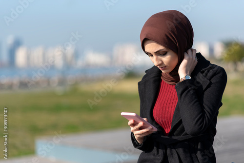 muslim young woman typing message with her smartphone
