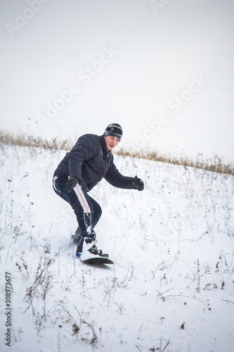 Happy young man with snowboard enjoying sunny weather in snowy mountains. Winter sport and recreation, leasure outdoor activities.