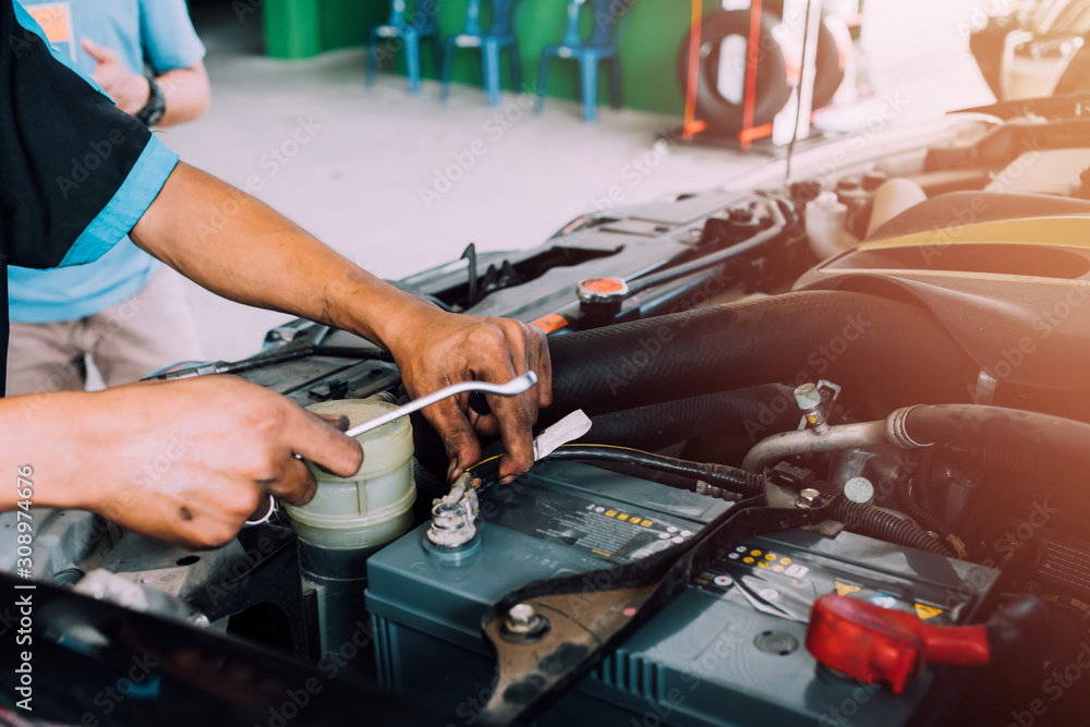 Mechanics use a wrench tool for changing car batteries. Fixing the car concept Mechanics use a wrench tool for changing car batteries. Fixing the car concept