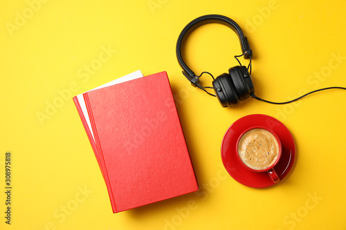 Red books, headphones and cup of coffee on yellow background, top view