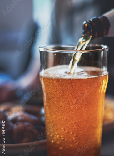 pouring beer in glass from bottle on bar or pub