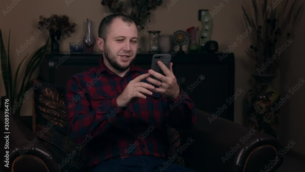 A young guy of European appearance sits in a chair in a plaid shirt, communicates via video link. Answers questions from subscribers. The concept of social networking blogs. A young guy of European appearance sits in a chair in a plaid shirt, communicates via video link. Answers questions from subscribers. The concept of social networking blogs.