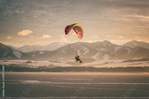Motor paraglider over the lake with mountains and sky on background, winter sunset landscape, tourist attraction, Liptovska Mara, largest water reservoir in Slovakia (Slovensko), travel destination