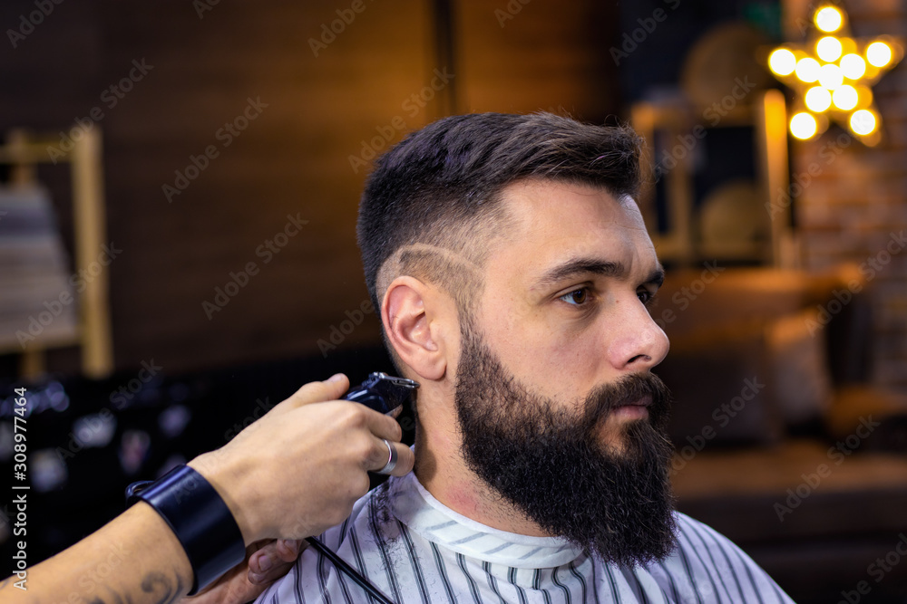Step 3. Getting perfect shape step by step. Hair styling and cutting with  trimmer. Young apprentice giving haircut to bearded man at barber shop.  Advertising and barber shop concept. Stock Photo |