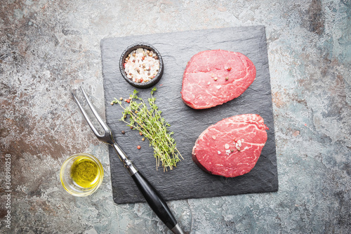 Fotografija Raw marbled meat steak Filet Mignon with seasonings over stone background, top view