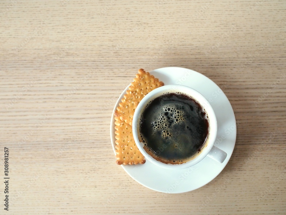 Picture seen from the top of hot black coffee in a white ceramic mug served with small pieces of bread. Picture seen from the top of hot black coffee in a white ceramic mug served with small pieces of bread.