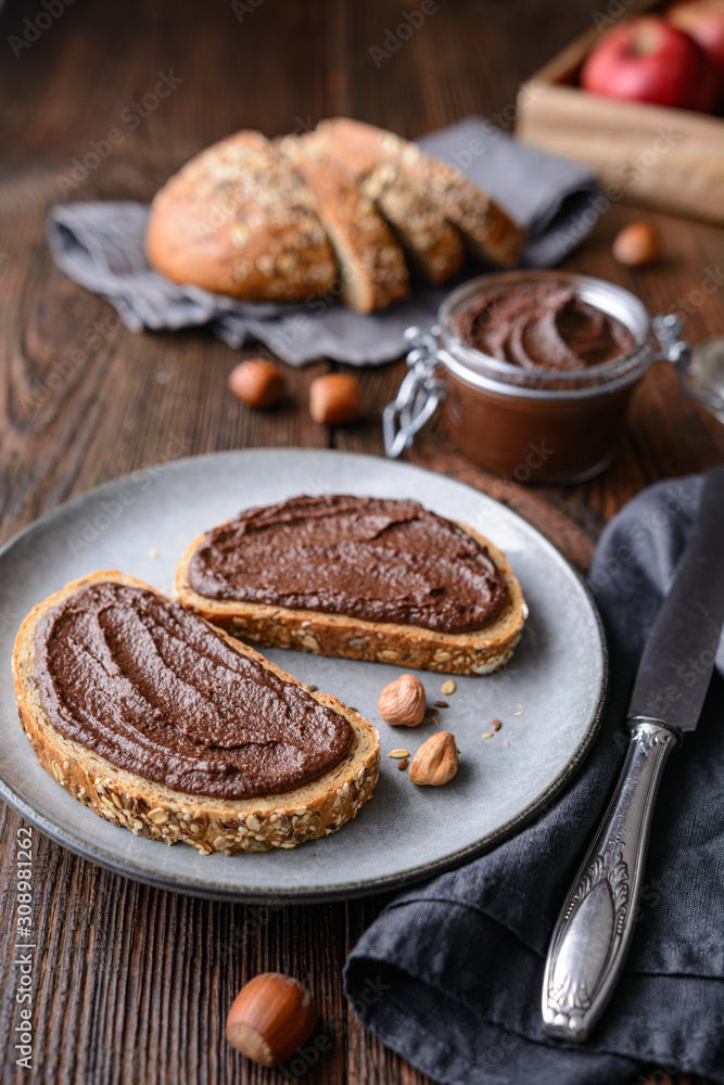 Healthy breakfast, slices of whole grain bread with apple spread made from cocoa powder, roasted ground hazelnuts and dark chocolate Healthy breakfast, slices of whole grain bread with apple spread made from cocoa powder, roasted ground hazelnuts and dark chocolate
