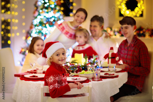 Family with kids having Christmas dinner at tree