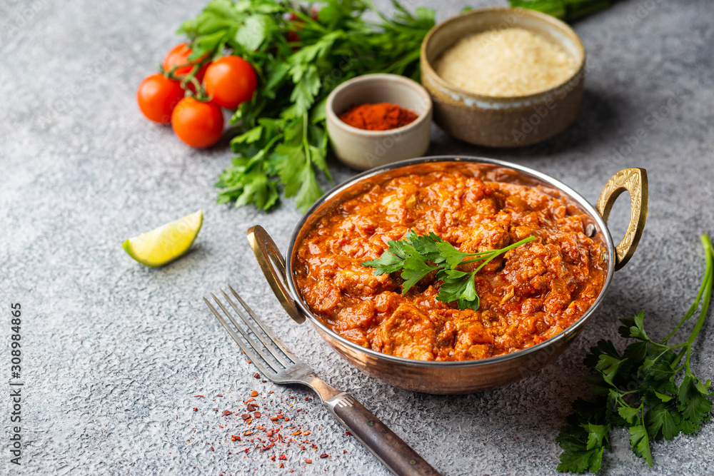 Chicken meat with tikka masala sauce, spicy curry food in iron copper pot with seasonings Chicken meat with tikka masala sauce, spicy curry food in iron copper pot with seasonings