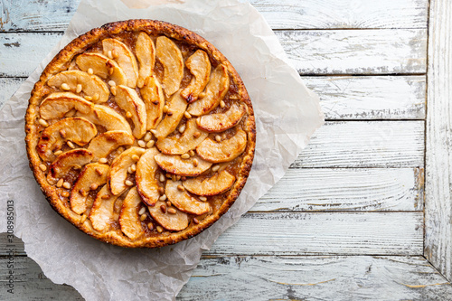 Homemade delicious fresh baked rustic apple pie on white wooden background, top view photo