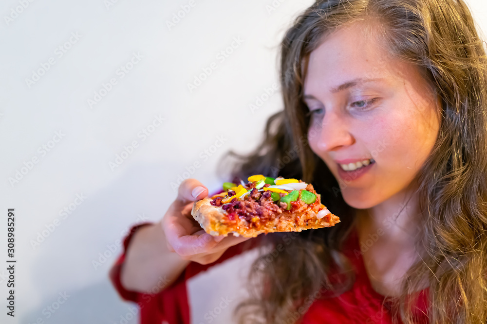 Young girl happy woman holding eating pizza slice with tomato sauce and toppings melted orange vegan cheddar cheese and meat crumbles sausage