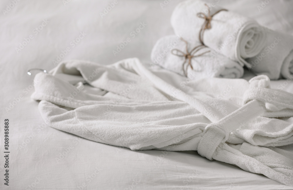 Obraz premium Clean soft bathrobe and towels on bed