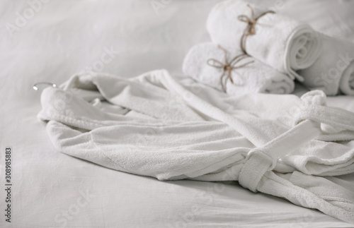 Clean soft bathrobe and towels on bed