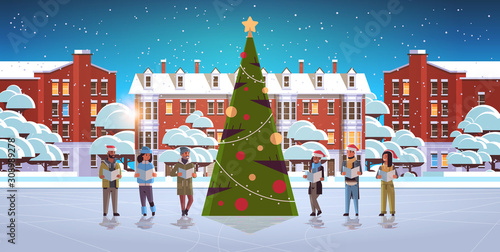 mix race people reading books merry christmas happy new year holiday celebration concept men women wearing santa hats standing near fit tree modern cityscape background horizontal full length vector