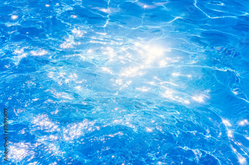 Blue ripped water in swimming pool. background the surface of the water. texture, blue water, bright rays of the sun