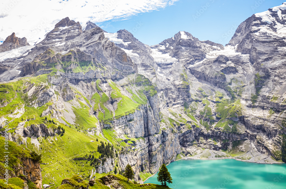 Amazing top view of Oeschinensee lake by Kandersteg, Switzerland. Turquoise lake surrounded by steep mountains and rocks. Swiss Alps. Switzerland in the summer season. Tourist destinations