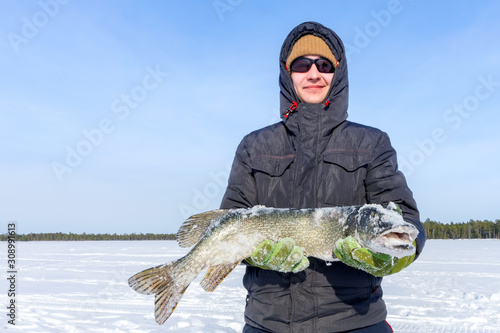man holds a large fish pike in winter. Winter fishing catch trophy outdoor activities hobby