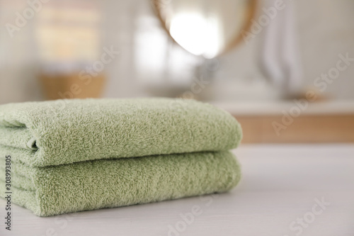 Stack of clean towels on white wooden table in bathroom